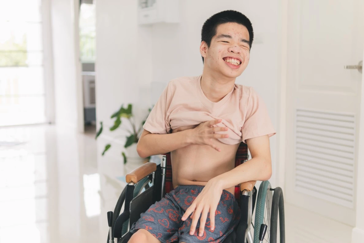 Disabled boy in wheelchair sitting at home smiling