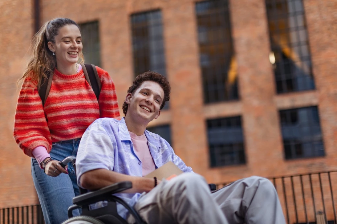Support worker pushing disabled boy in wheelchair outside