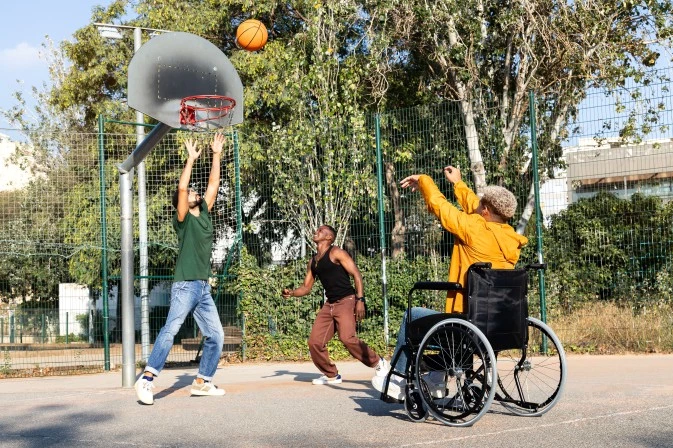 Three friends, one disabled, playing a game of basketball outside