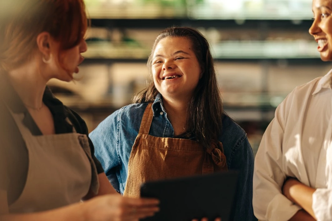 Happy girl with down syndrome smiling and talking with colleagues